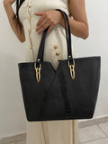 Tote V-Cut Negra Textura Mixta con modelo vista frontal sosteniendo detalle herrajes dorados