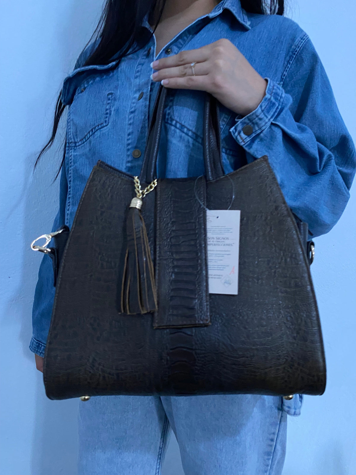 Tote Mixta Café Oscuro sostenida vista lateral detalle pies metálicos y bolsillo trasero