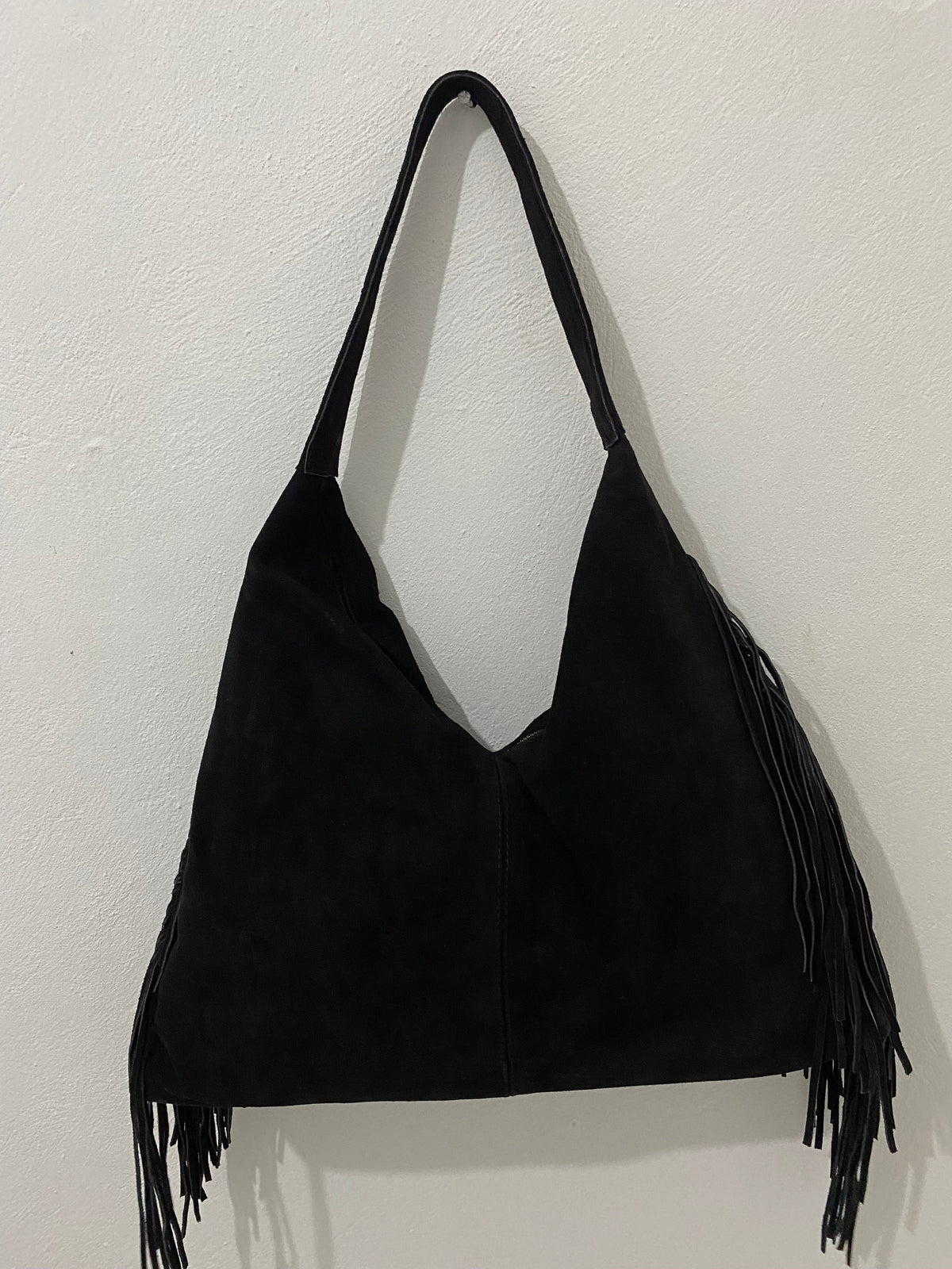 Bolsa Bohemia negra con flecos colgada en pared