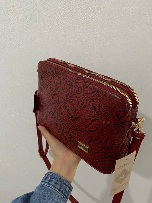 Crossbody Floral Vino sostenida en mano vista lateral detalle grabado